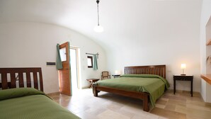 Een slaapkamer met een schuine kap, een bed met een houten hoofdbord, een nachtkastje en een stoel.