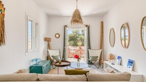 Ein modernes Wohnzimmer mit einer Couch, Sesseln, einem Couchtisch und Kunstwerken an den Wänden.