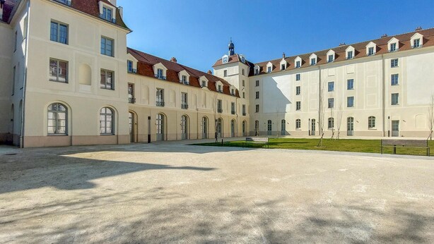A large, historic building with multiple wings and a central courtyard.
