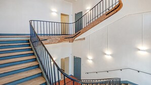 A multi-level interior with a wooden staircase, metal railings, and a modern light fixture.