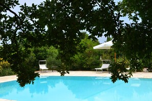 A swimming pool with two sun loungers and a covered area, surrounded by trees and greenery. - Trullo 'Corte Del Camedrio  2' with Shared Terrace, Wi-Fi and Air Conditioning (Ostuni)