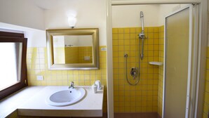 A bathroom with a sink, mirror, and shower.