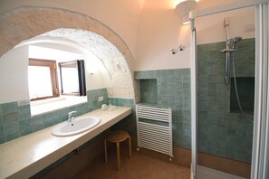 A bathroom with a sink, mirror, towel rack, shower, and a small stool. - Trullo 'Corte Del Camedrio  Triplo' with Shared Terrace, Wi-Fi and Air Conditioning (Ostuni)