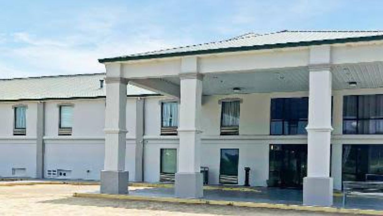 A two-story building with a covered outdoor area, large windows, and a flat roof.