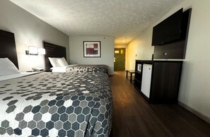 Una habitación de hotel con una cama grande, un escritorio, un televisor y un refrigerador.