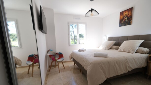 Une chambre à coucher avec un lit, une chaise, une fenêtre et un tableau accroché au mur.
