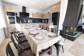 A modern kitchen with built-in appliances and a dining area set for six. - Air-conditioned villa heated pool Alpilles view St-Rémy (Saint Remy de Provence)