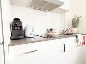 A modern kitchen with a coffee maker, toaster, and a plant on the counter.