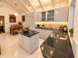 A modern kitchen with a central island, built-in appliances, and a dining area with a table and chairs. - House Dalma (Dubrovnik)