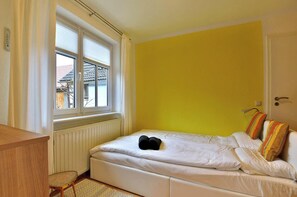 Ein Schlafzimmer mit einem Bett, einem Fenster, einer Heizung und einem Holztisch.