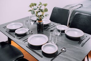 Un tavolo da pranzo apparecchiato con piatti, ciotole, bacchette e un vaso con piante.