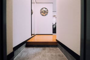 Un corridoio con pavimento in legno, pareti bianche e un elemento decorativo circolare al muro.