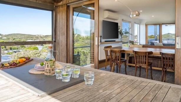 Eine Holzterrasse mit Esstisch, einer Wasserflasche und Gläsern.