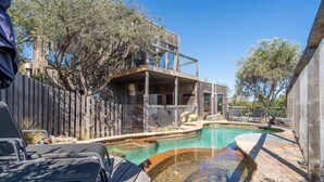 Ein Garten mit Swimmingpool, Holzterrasse und einem Haus mit Balkon.