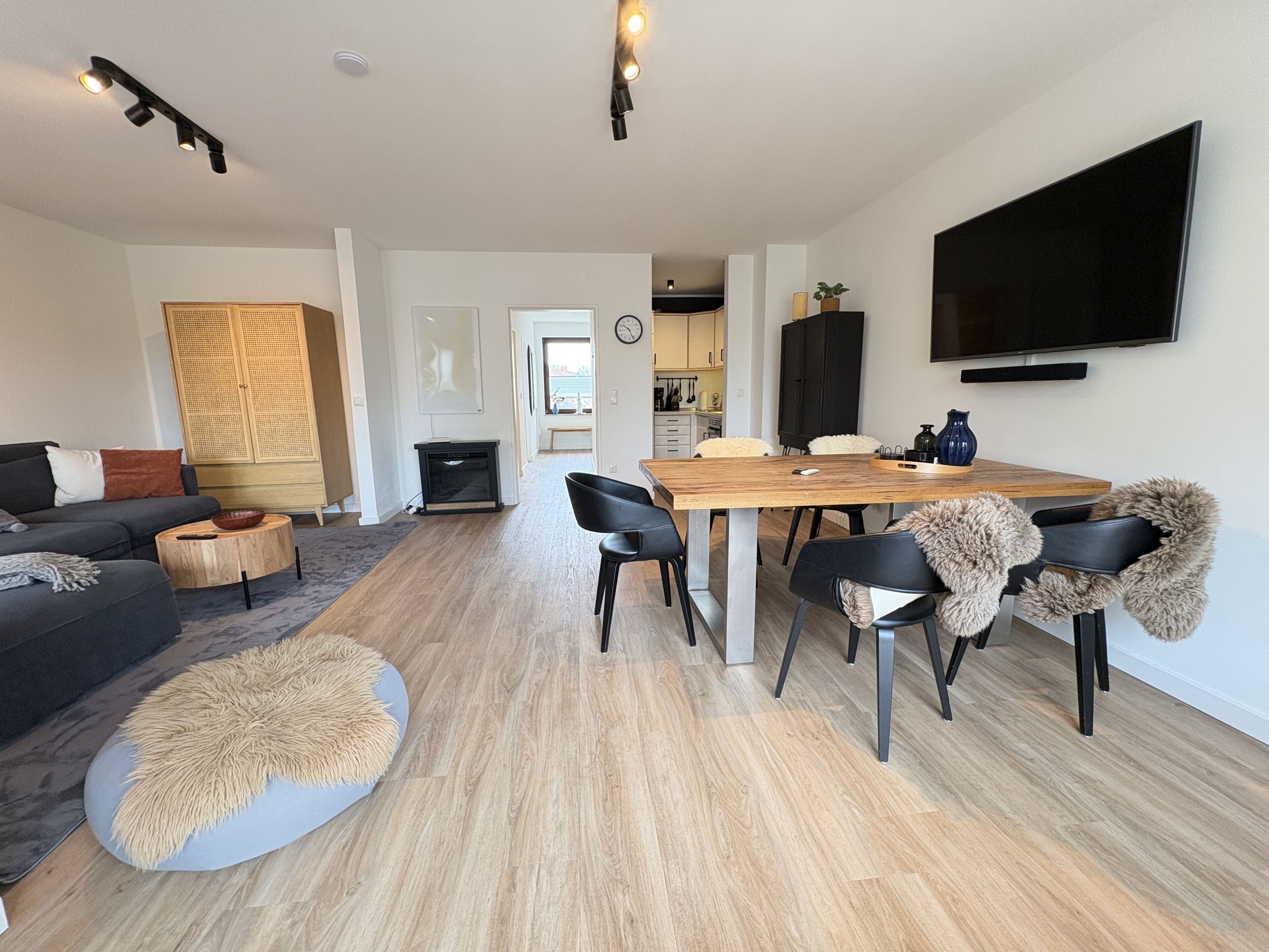 A modern living room with a sofa, coffee table, and dining area with chairs.