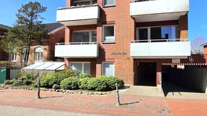 Ein mehrstöckiges Wohnhaus mit Balkonen, einer Garage und einer Ziegel-Fassade.