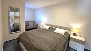 Ein Schlafzimmer mit Bett, Nachttischen, einem Spiegel, einer Couch und einer Deckenleuchte.