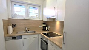 Eine kompakte Küche mit Geschirrspüler, Herd und einem Fenster über der Spüle.