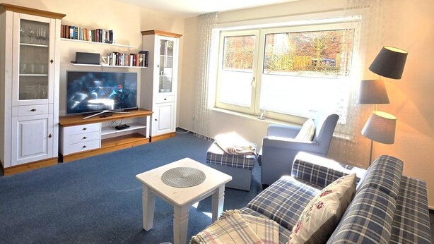 Ein Wohnzimmer mit Sofa, Couchtisch, Fernseher und Bücherregal.