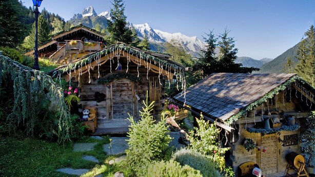 Ein rustikales Blockhaus mit Holzbalkon, einem kleinen Garten und Bergblick.