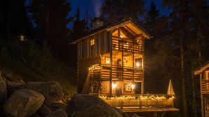 Eine Holzhütte mit Balkon, umgeben von Felsen und Bäumen.