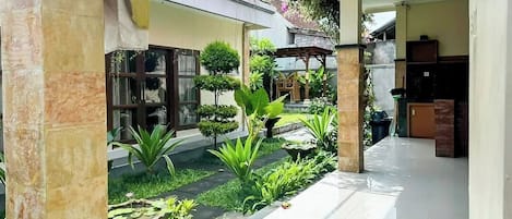 Un patio con fuente, plantas en macetas y una pérgola.