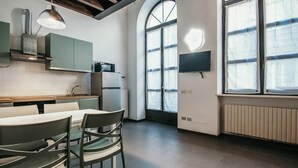 Een moderne keuken met een eethoek, grote ramen en een flatscreen televisie.