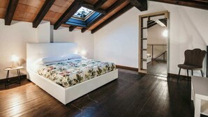 Een slaapkamer met dakraam, een bed, een stoel en een bureau.