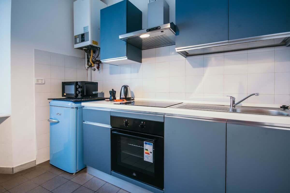 Cocina compacta con microondas, hervidor, horno y lavabo.