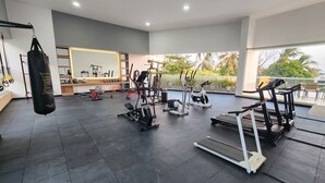 A gym with various exercise equipment, a punching bag, and a view of palm trees. - Ocean view + Direct beach view in Pozos colorados (Urb Plenomar)