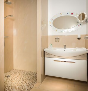 Ein Badezimmer mit Dusche, Waschbecken, Spiegel und Fliesenboden.