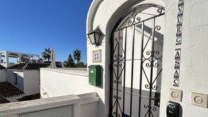 A white building with a metal gate, a green trash bin, and a number '23' sign. - Rabat 23 in Oasis de Capistrano Nerja (Nerja)
