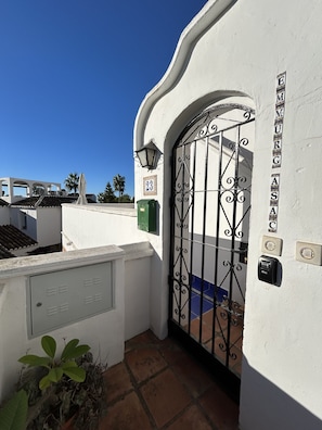 A white building with a metal gate, a green trash bin, and a number '23' sign. - Rabat 23 in Oasis de Capistrano Nerja (Nerja)
