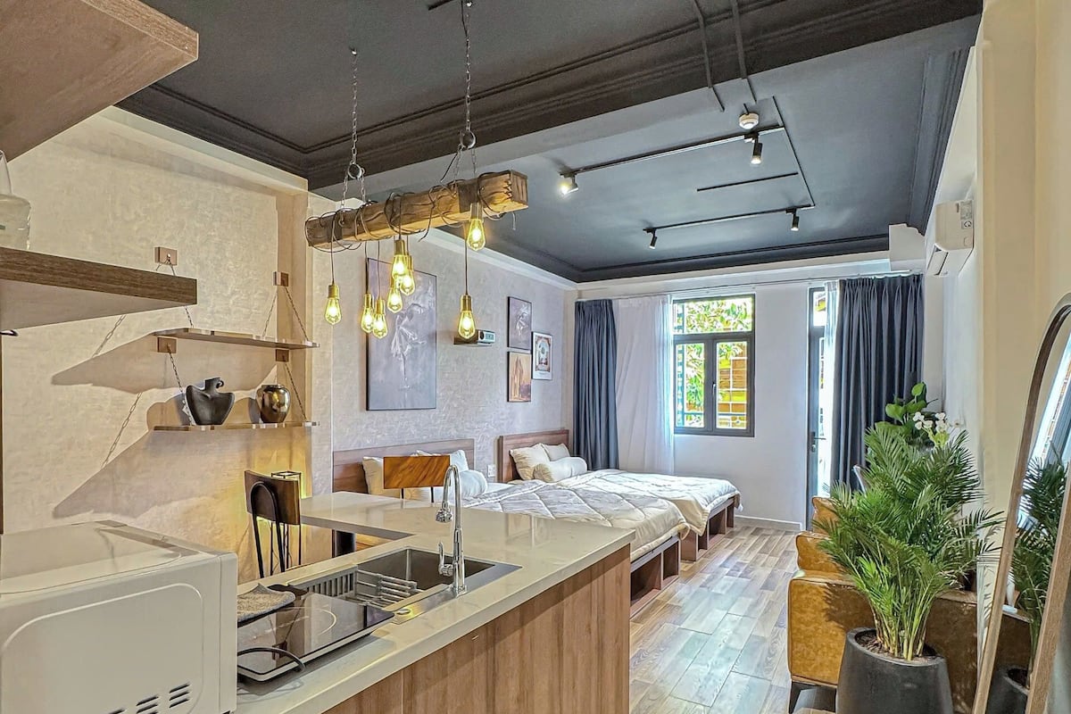 Una cocina moderna con una isla integrada, un rincón de comedor con sofá y un amplio ventanal con cortinas.