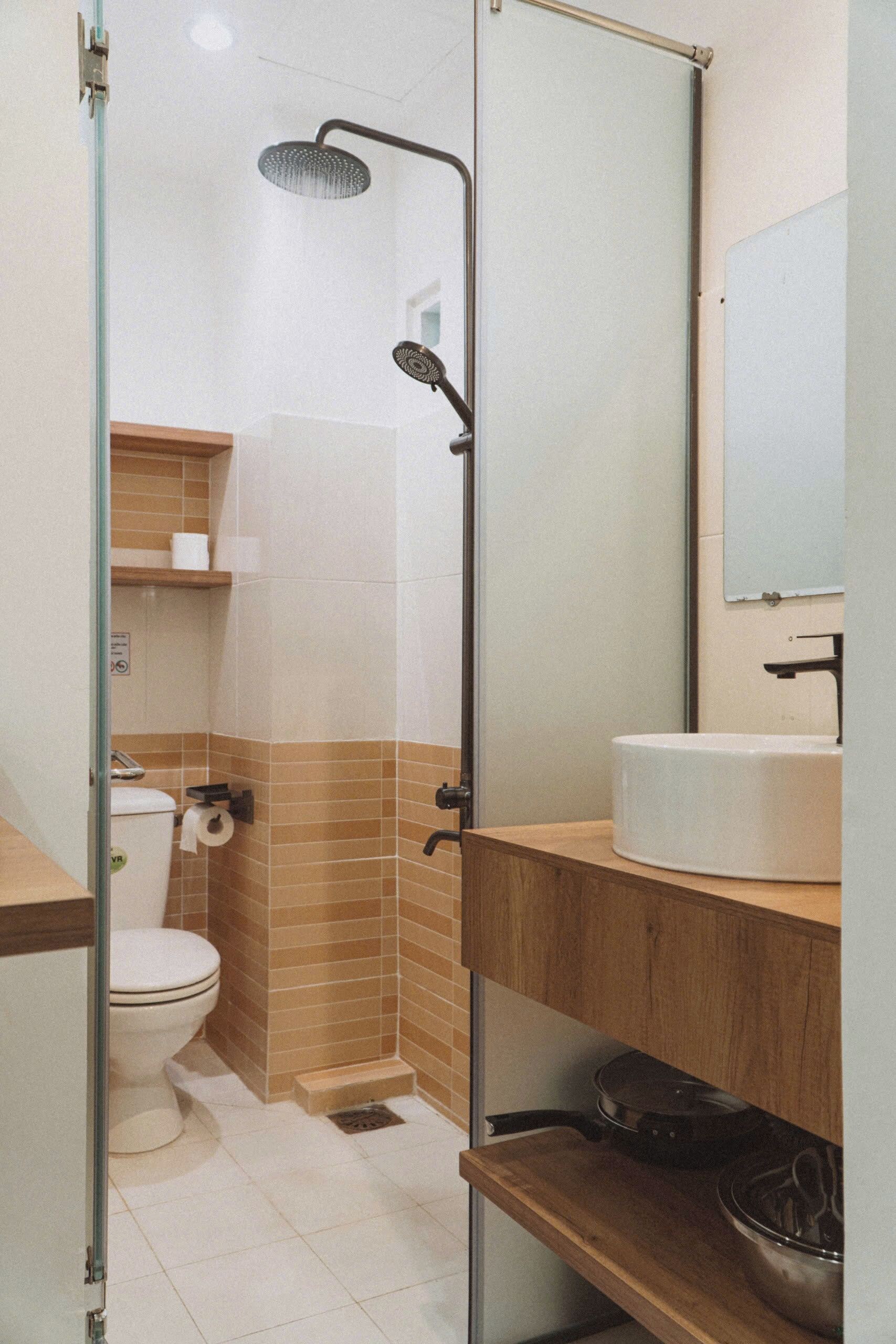 A bathroom with a shower, toilet, sink, and a mirror.