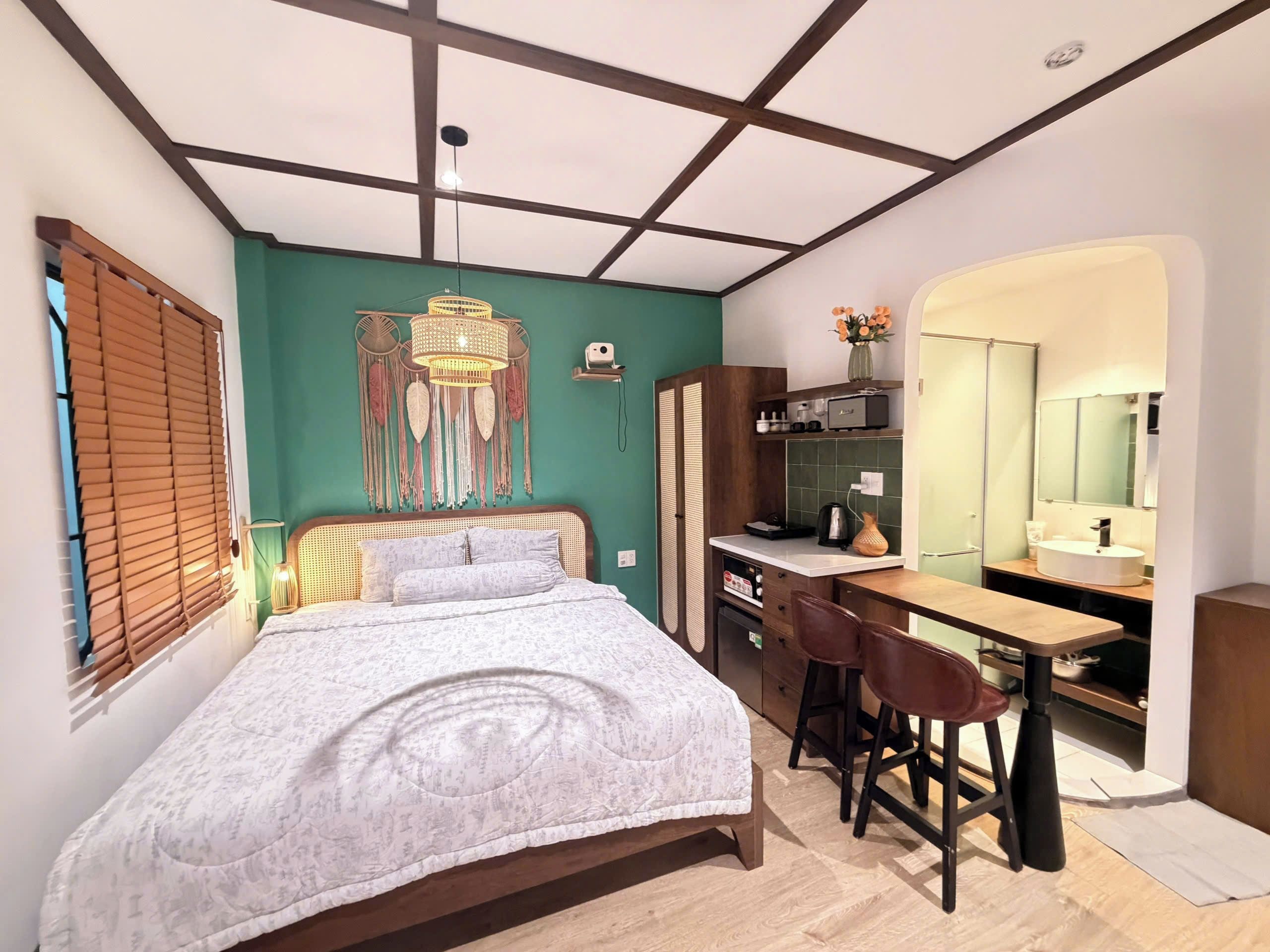 Ein Schlafzimmer mit Bett, Schreibtisch und Stuhl, einer Küchenzeile und einem Badezimmer mit Spiegel.