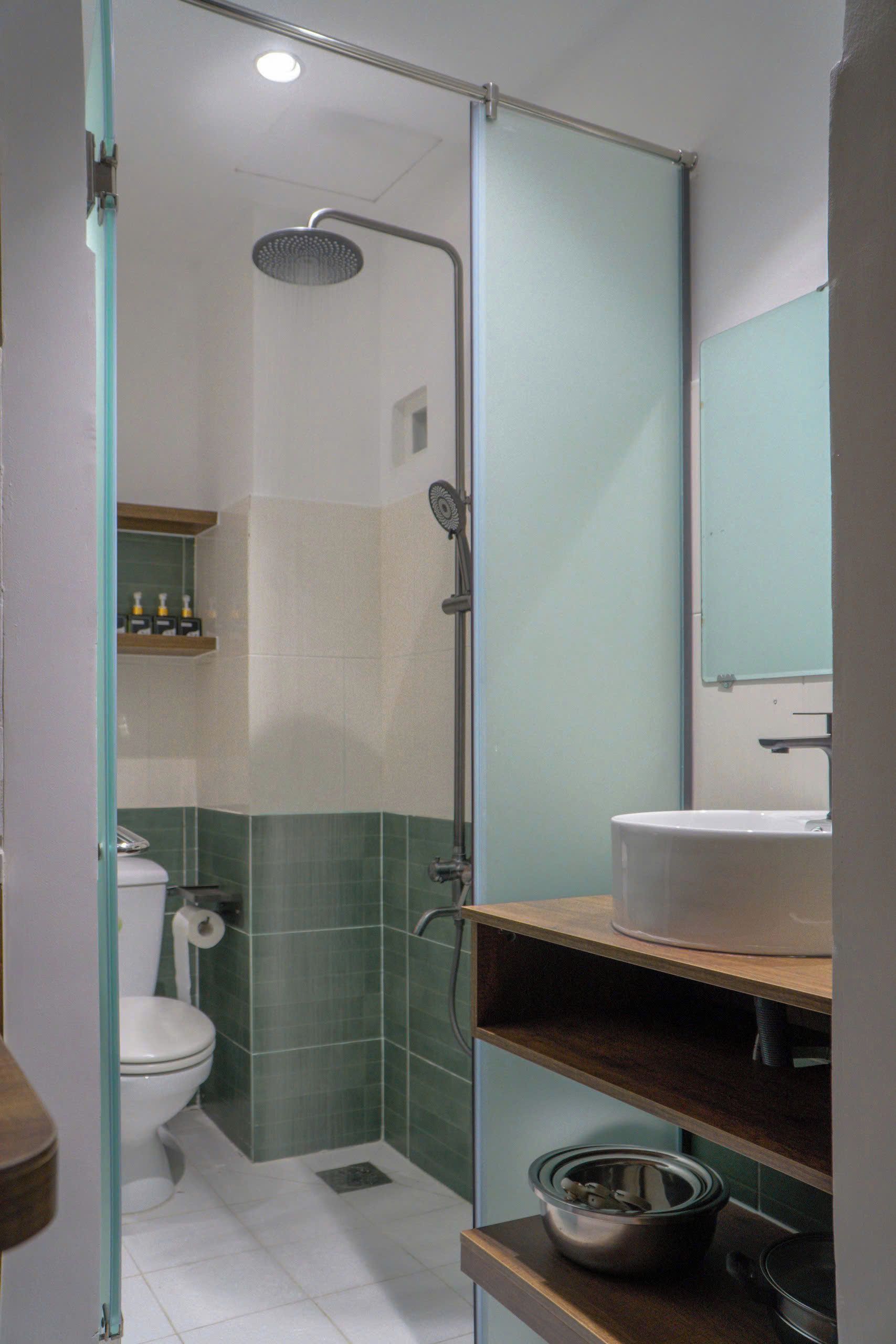 A bathroom with a glass shower enclosure, a toilet, a sink, and a mirror.