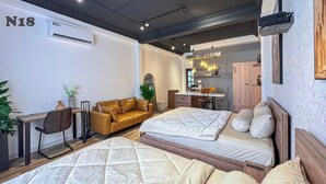 Une chambre d’hôtel équipée d’un lit, d’un bureau, d’un canapé, d’une kitchenette et d’un grand miroir.