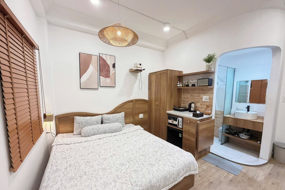 A bedroom with a bed, a wardrobe, a desk, and a bathroom.