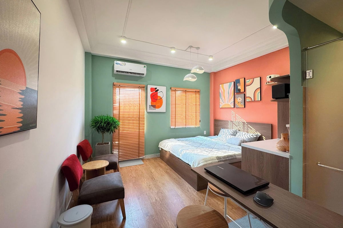 Un dormitorio moderno con cama, escritorio, silla y una pequeña mesa con una planta.