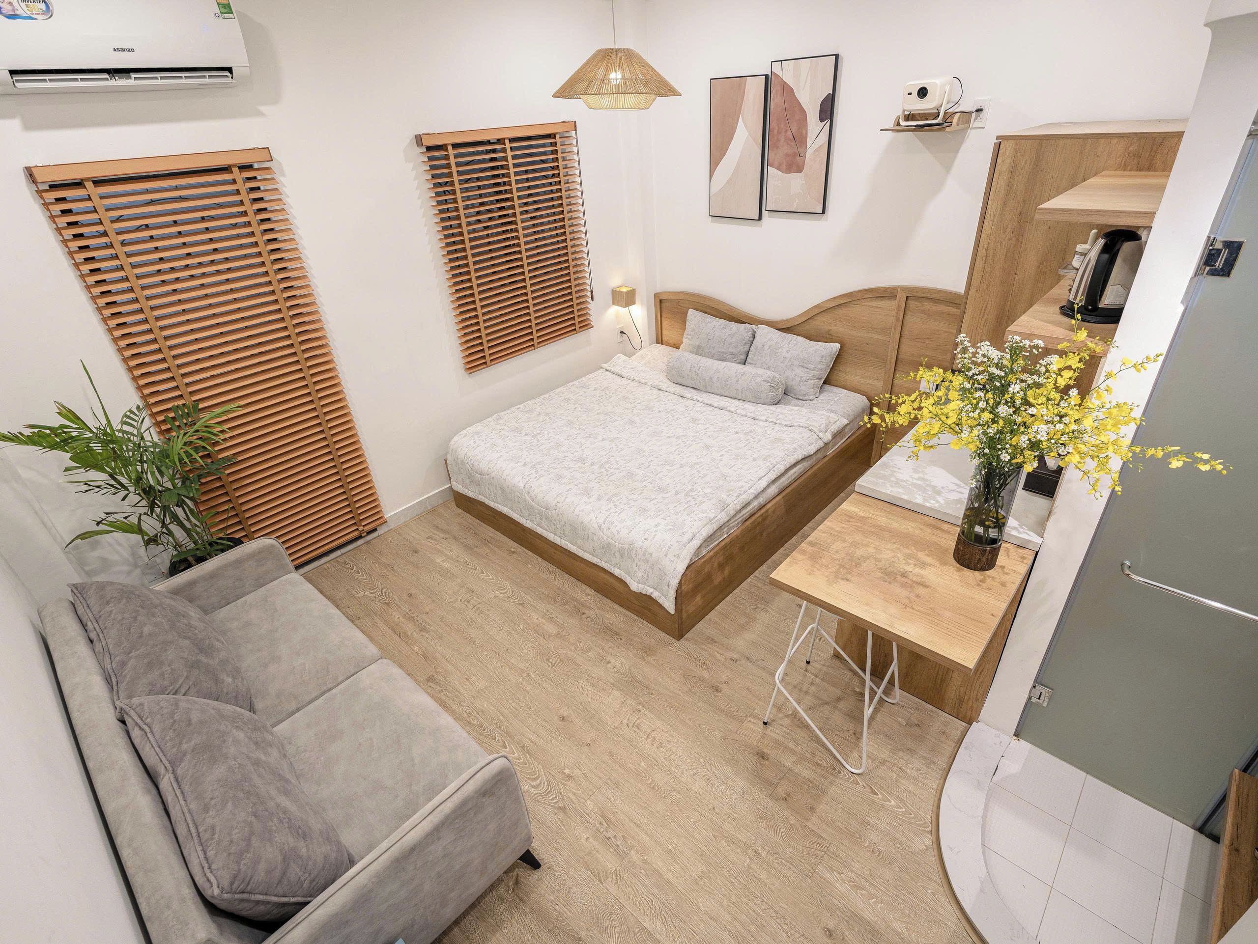 A modern bedroom with a bed, bedside table, and a seating area with a sofa.