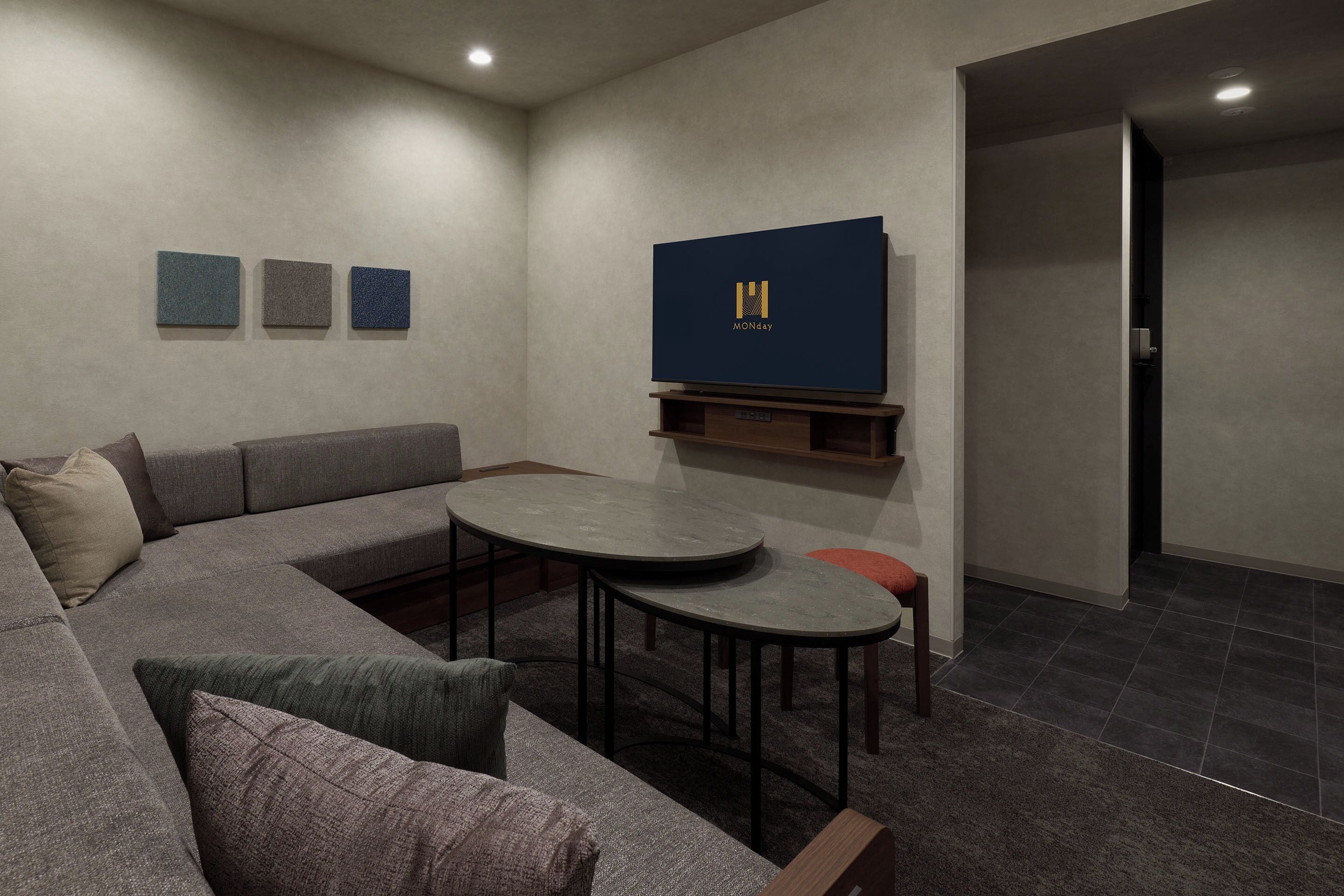 Ein modernes Wohnzimmer mit einem Ecksofa, einem runden Couchtisch und einem an der Wand befestigten Flachbildfernseher.