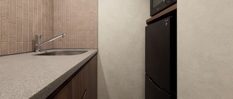 A kitchen with a granite countertop, a stainless steel sink, and a black refrigerator.