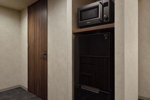 A room with a wooden door, a microwave, and a black cabinet with a control panel. - Premium MONday OSAKA SHINSAIBASHI (Osaka)