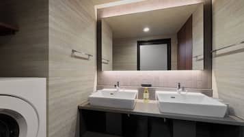 Un baño moderno con dos lavamanos, un espejo y un perchero para toallas.