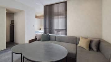 A modern living room with a sectional sofa, a round table, and a kitchen area visible through an open doorway.