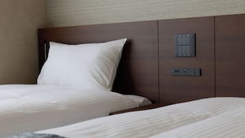 A hotel room with two beds, a headboard, and a control panel with buttons.