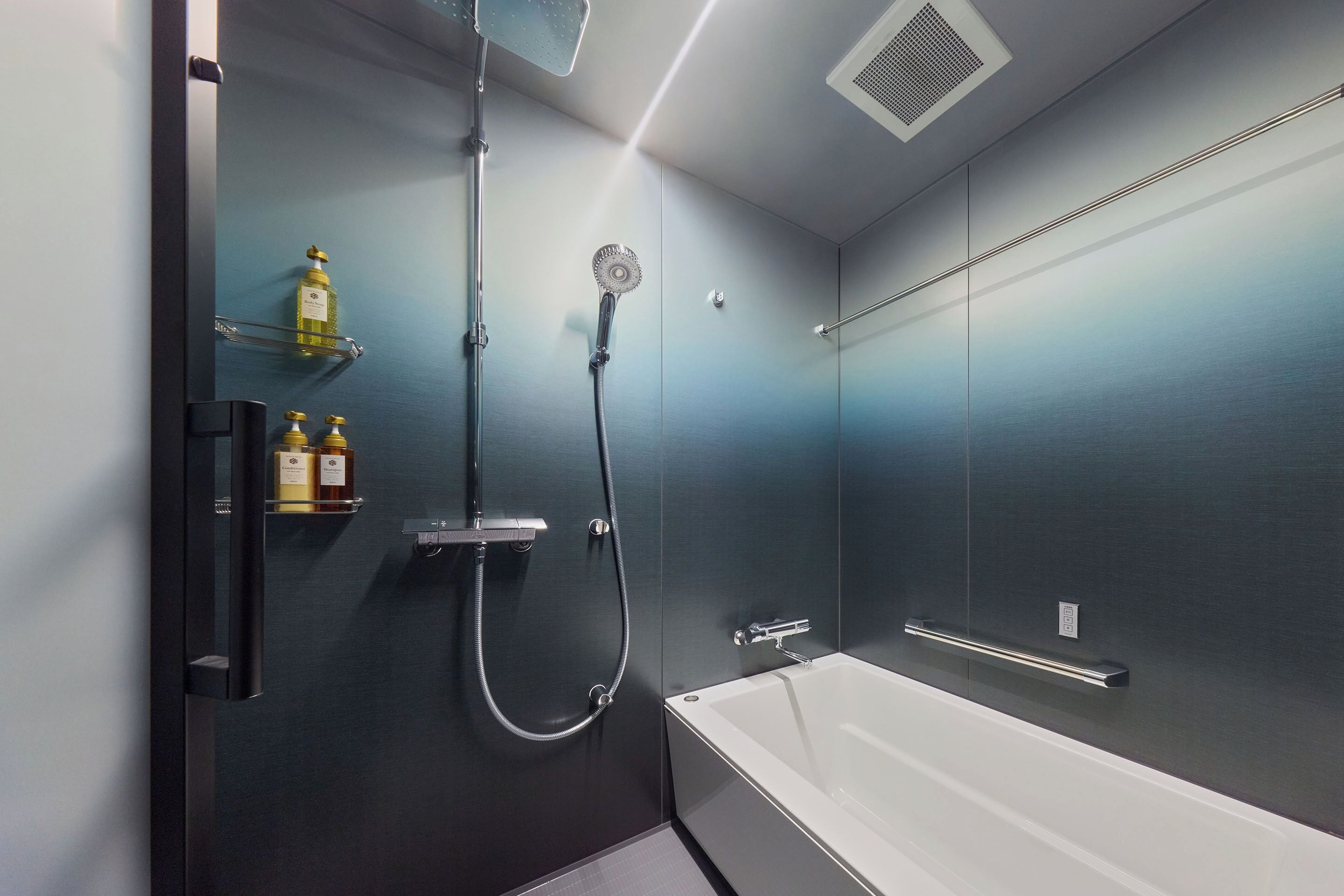 Une salle de bain moderne équipée d’une baignoire, d’une douche et d’une étagère où sont rangés les produits de toilette.