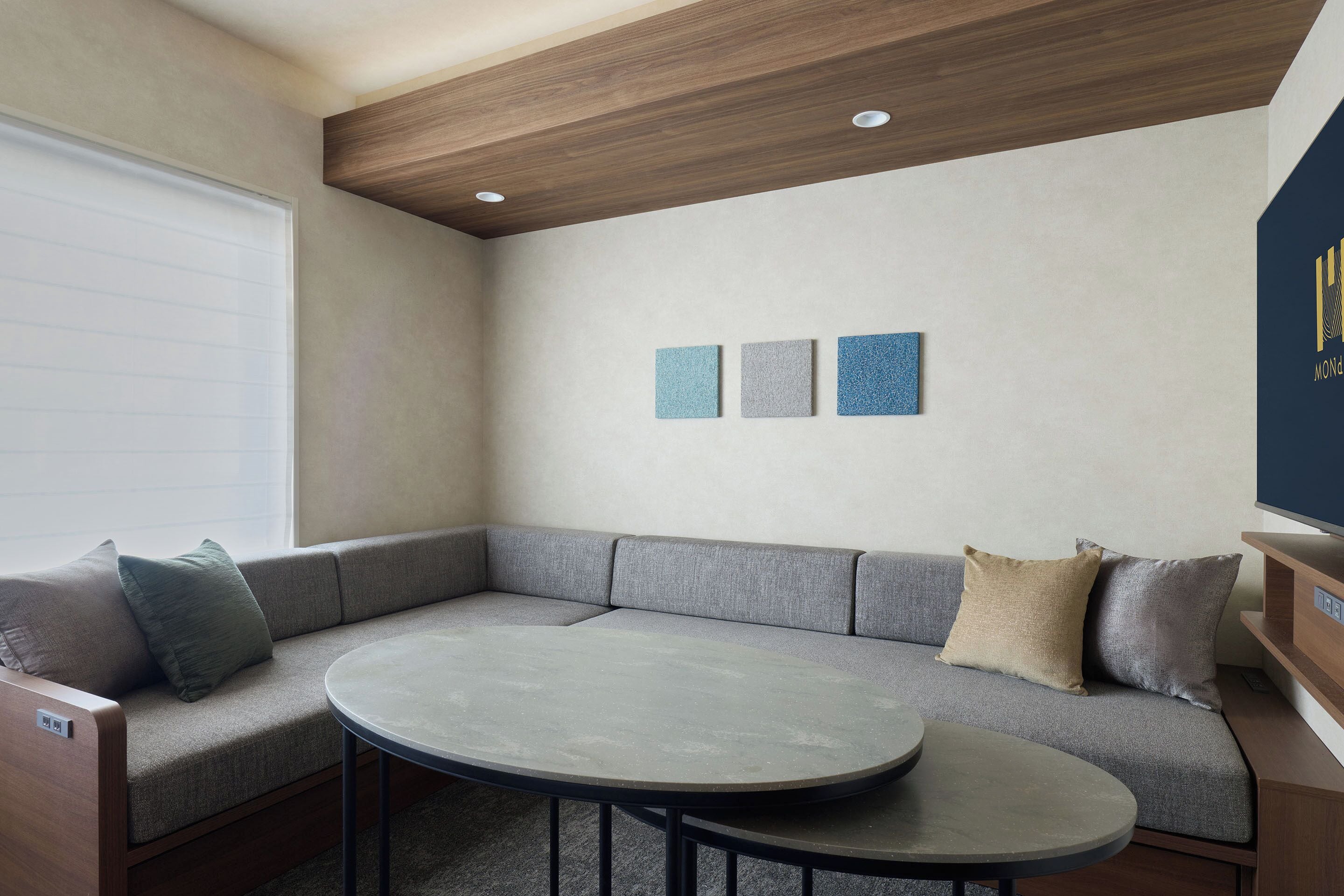 Una sala de estar moderna con un sofá seccional gris, una mesa redonda y un techo de madera.