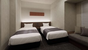 A hotel room with two beds, a sofa, a wall-mounted air conditioner, and a textured wall panel. - Premium MONday OSAKA SHINSAIBASHI (Osaka)